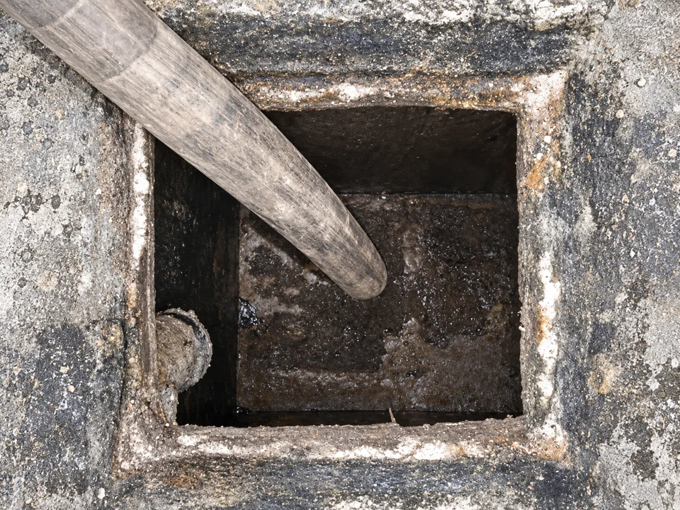 Siphoning hose inside an open concrete septic tank